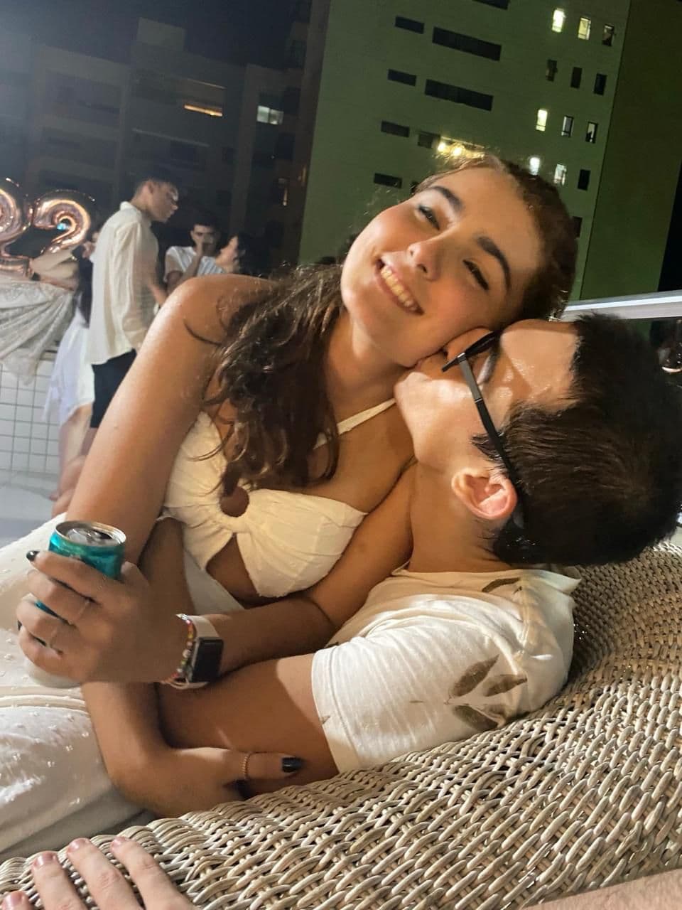 Marina abraçada com Lucas em uma festa à noite